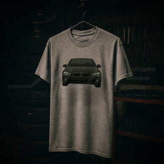 M Sedan Cartoon Tee hanging in garage workshop with tools and stacked wheels – automotive lifestyle apparel