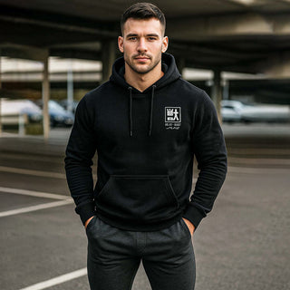 Male model wearing black M Line Manga Series Vol. 01 hoodie with kanji chest print, urban parking-lot background.