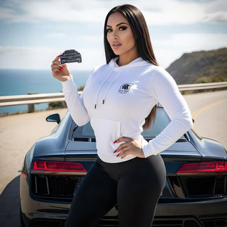 Model holding Audi R8 V10 silhouette air freshener beside supercar rear with ocean backdrop
