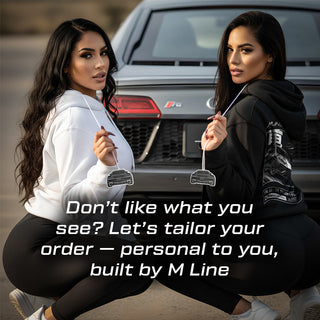 Two models holding Audi R8 4S V10 silhouette air fresheners beside supercar rear – M Line lifestyle branding