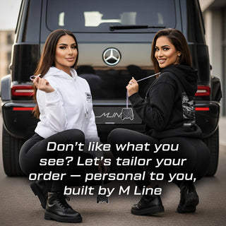 Two models holding Mercedes G Wagon G63 G-Series silhouette air fresheners in front of luxury SUV – M Line lifestyle branding.